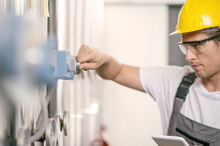 Mann mit Bauhelm prüft Heizung