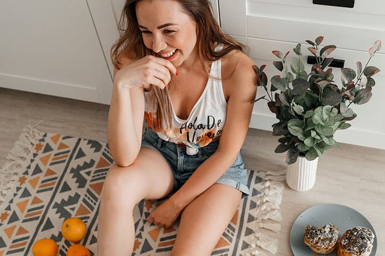 Glückliche Frau sitzt auf einem Teppich auf dem Boden