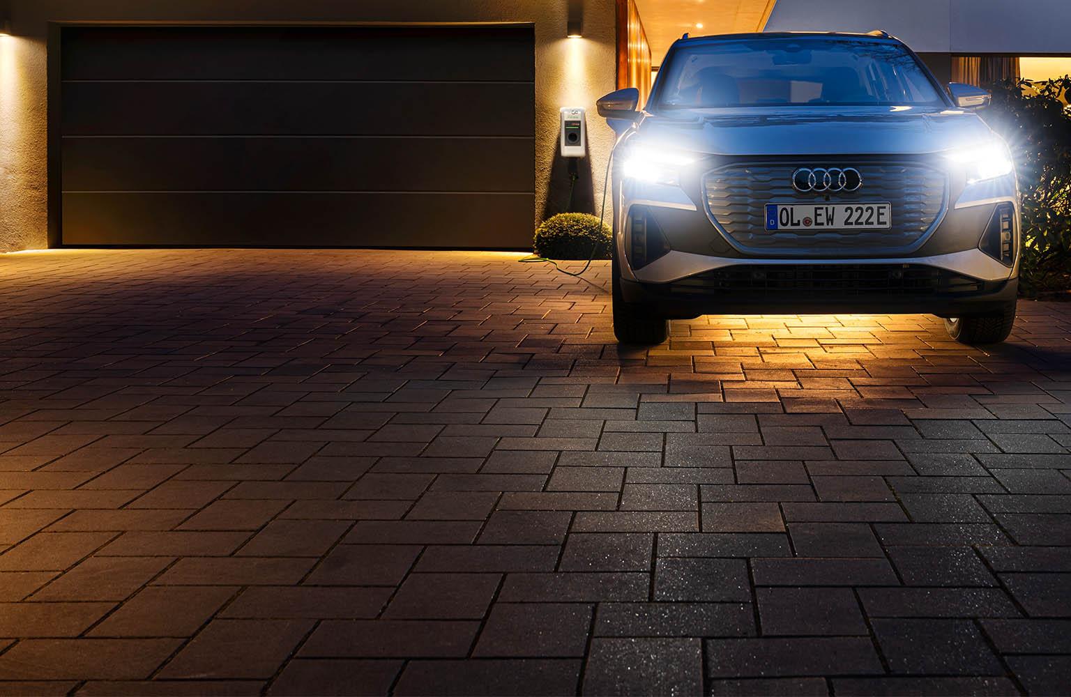 Auto vor einem Haus mit Wallbox im Hintergrund.