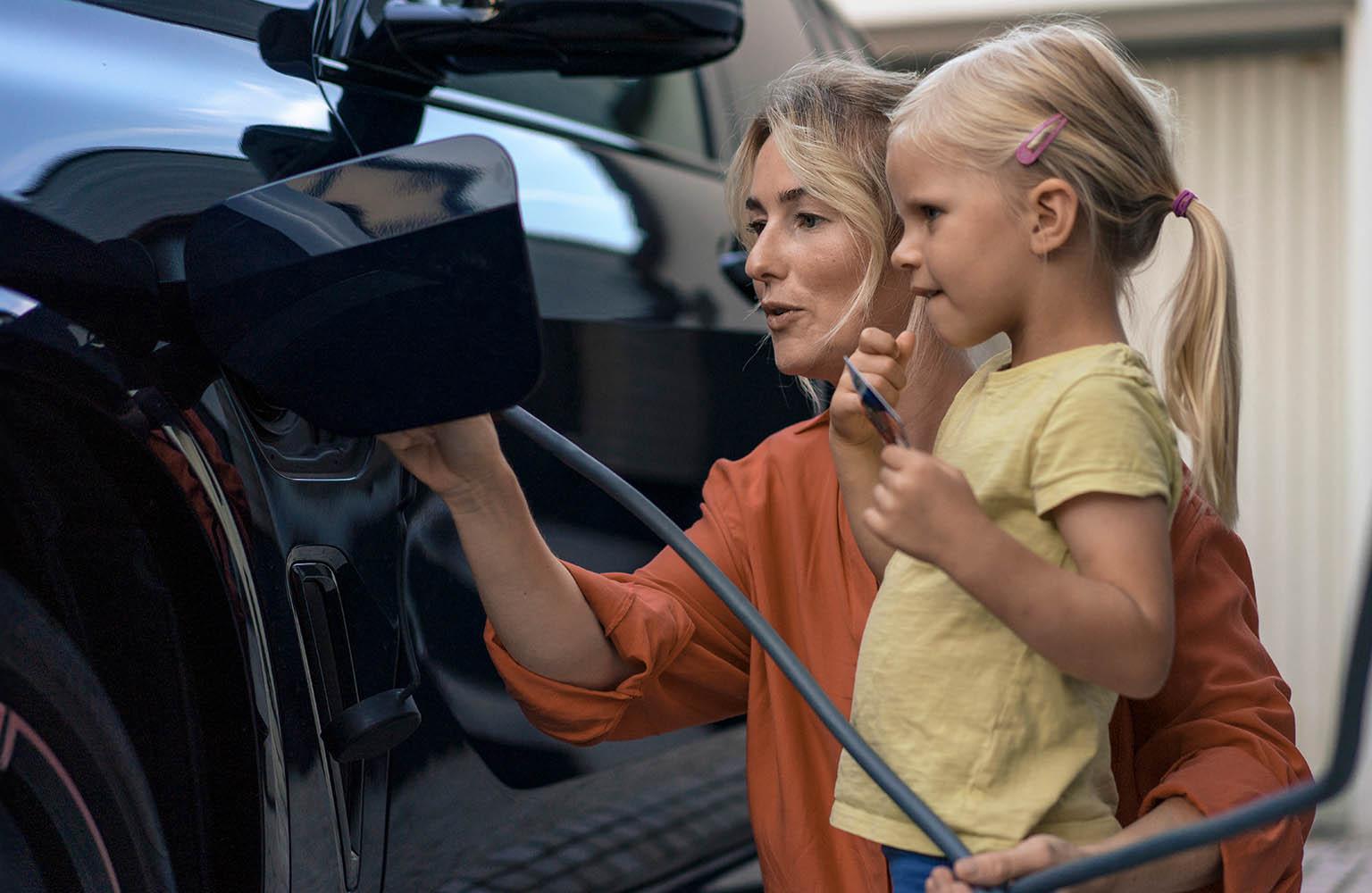 Mutter mit Kind lädt Elektroauto