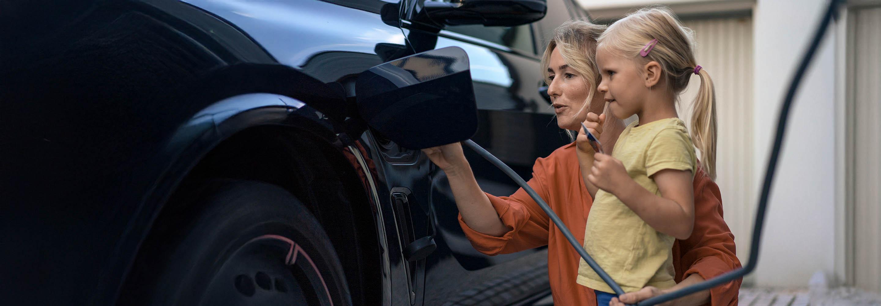 Mutter mit Kind lädt Elektroauto