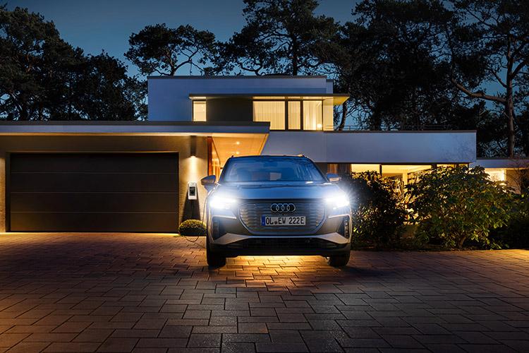 Auto vor einem Haus mit Wallbox im Hintergrund.