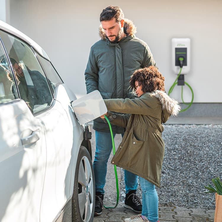 Auto vor einem Haus mit Vater und Sohn und Wallbox im Hintergrund