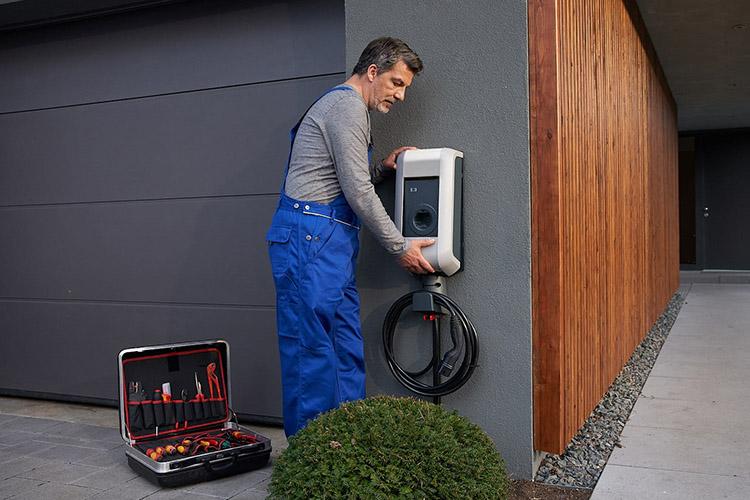 Handwerker bringt Wallbox an Hauswand an.