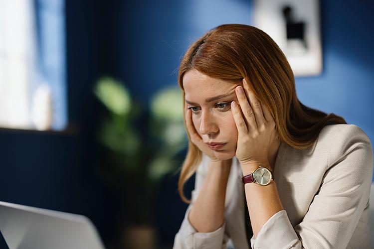 Frau schaut verzweifelt auf ihren Laptopbildschirm