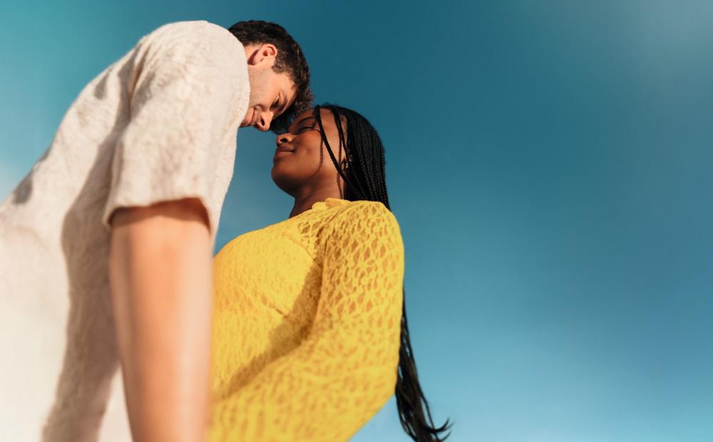 Ein Paar schaut sich vor blauem Himmel verliebt an