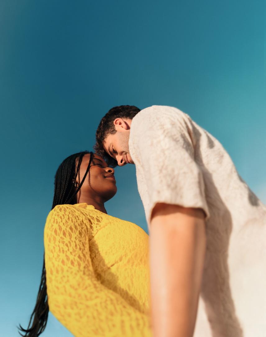 Ein Paar schaut sich vor blauem Himmel verliebt an