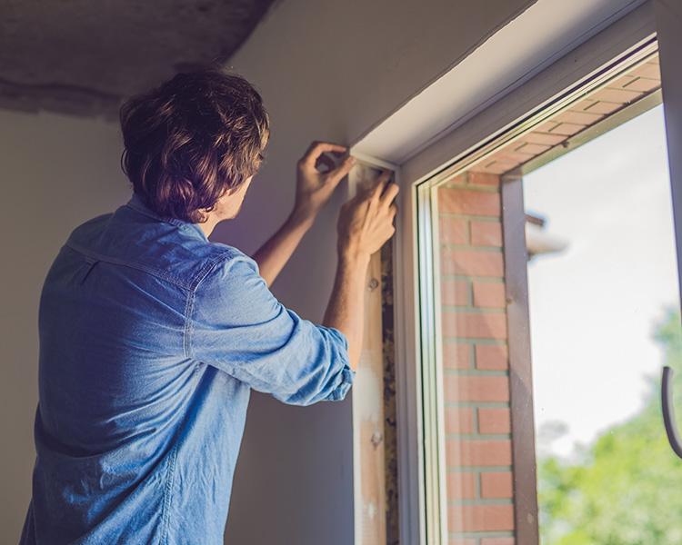 Mann dichtet Fenster ab