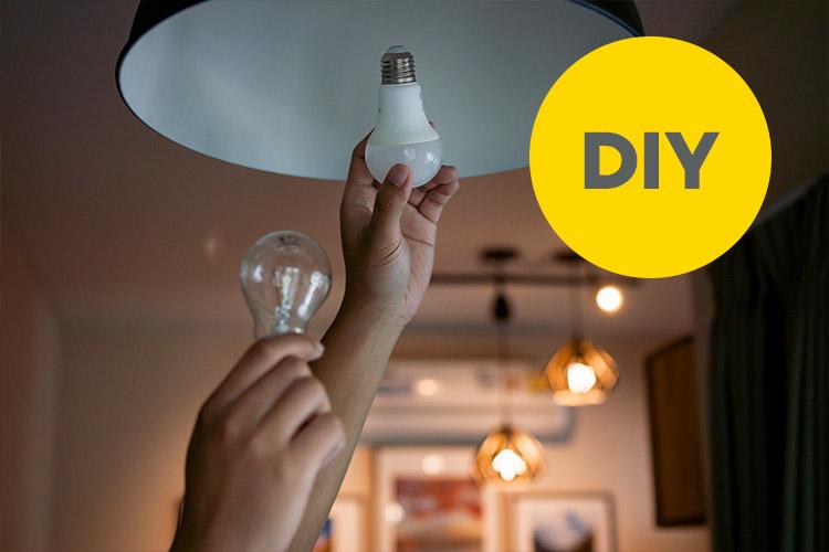 Hand schraubt eine Energiesparbirne in eine Fassung