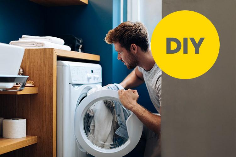 Mann packt Wäsche in die Waschmaschine