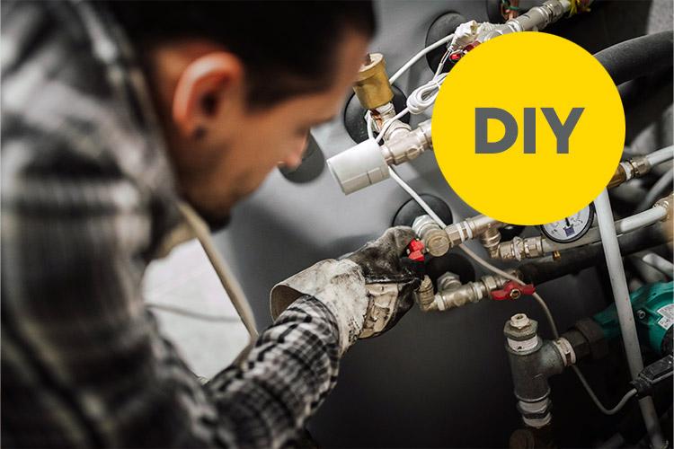 Techniker schraubt an einer Heizung.