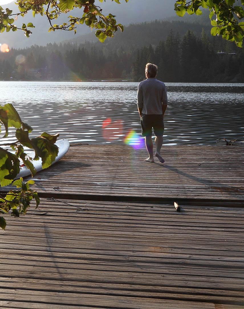 Mann blickt auf einem Steg auf einen See