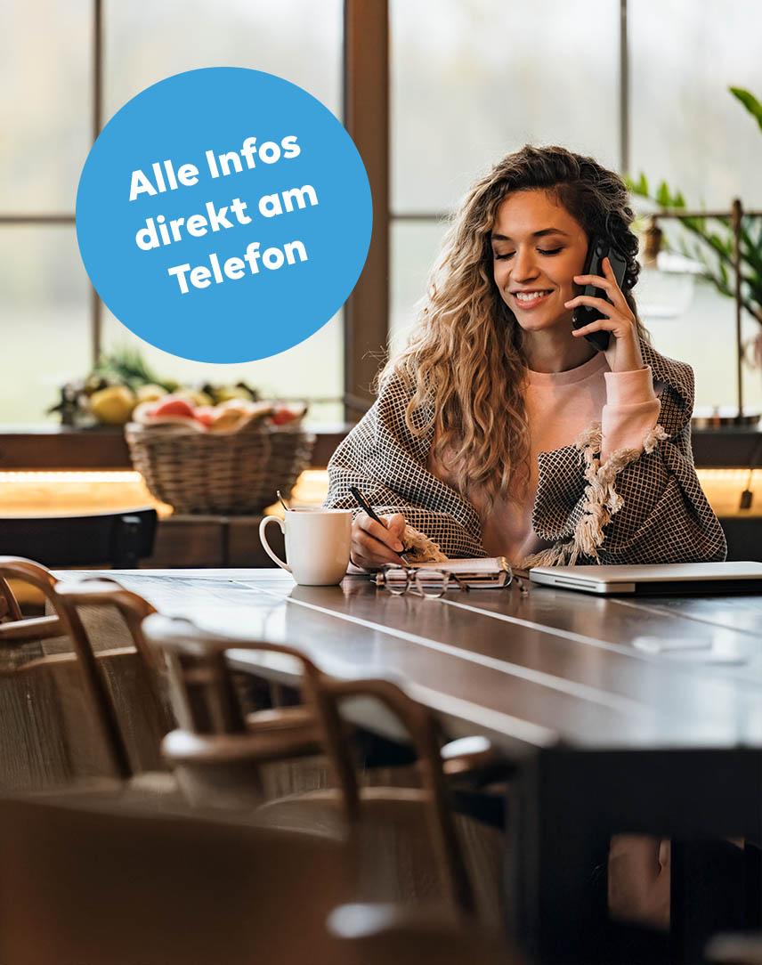 Frau telefoniert am Handy und macht sich dabei Notizen