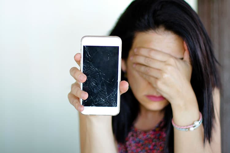 Frau hält verzweifelt kaputtes Smartphone in die Kamera