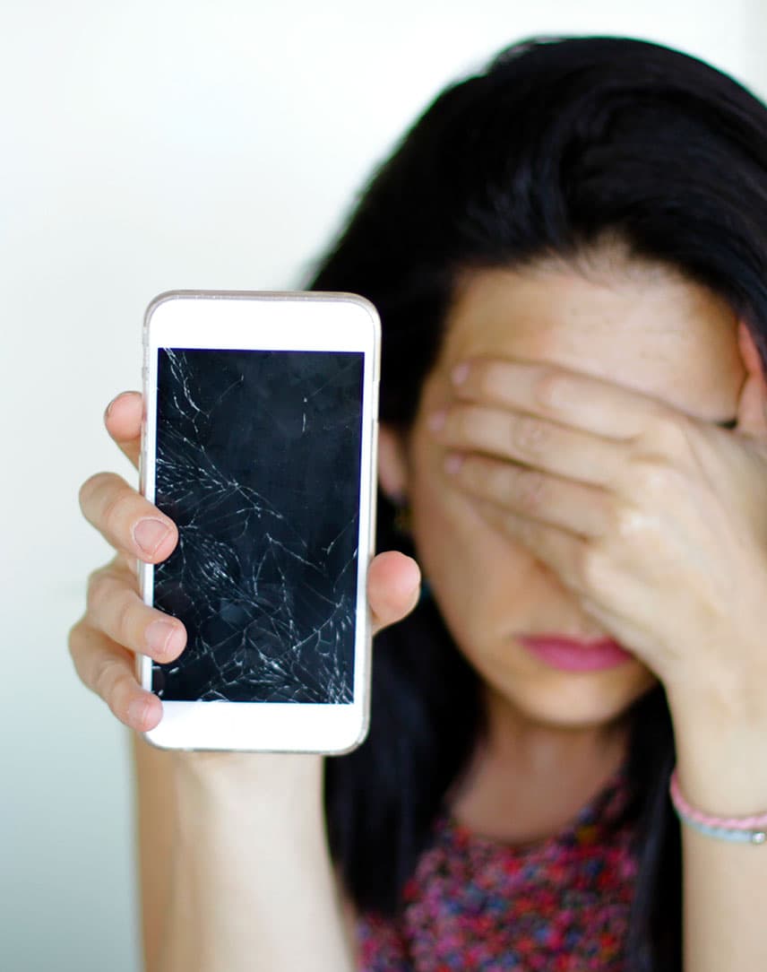 Frau hält verzweifelt kaputtes Smartphone in die Kamera