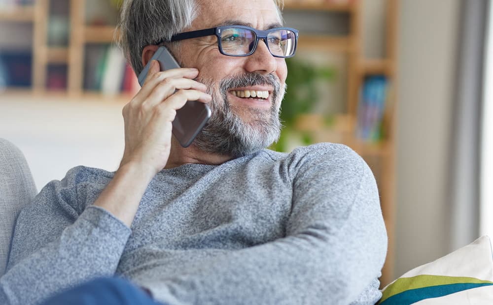 Mann auf dem Sofa telefoniert mit dem Smartphone.