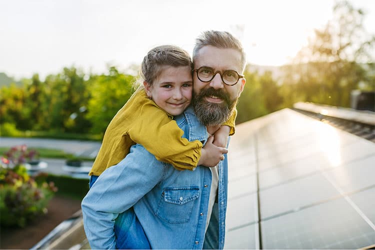 Vater und Kind glücklich auf dem Dach vor ihrer Solaranlage