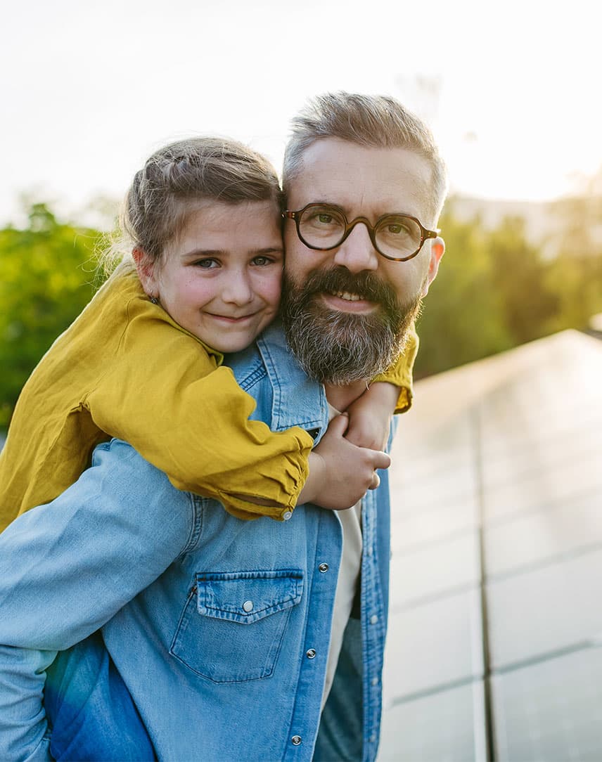 Vater und Kind glücklich auf dem Dach vor ihrer Solaranlage