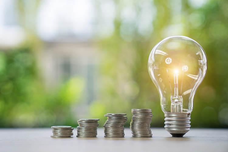 Aufgehäufte Münzen und Glühbirne