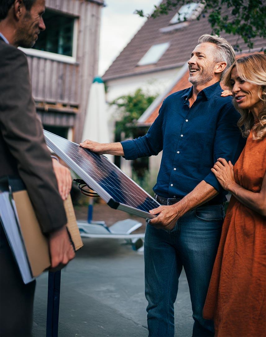 Vertreter übergibt Mann und Frau ein PV-Modul