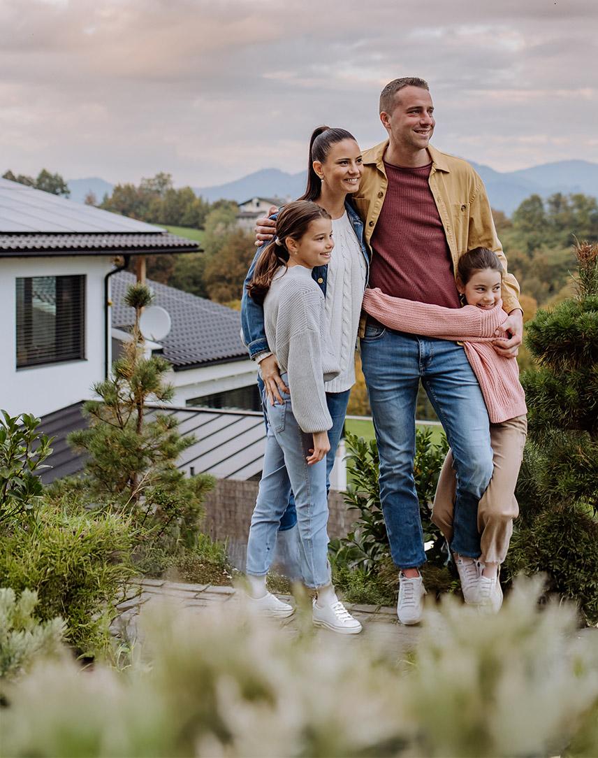 Familie steht vor einem Haus auf dem eine PV-Anlage angebracht ist