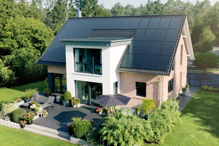 Haus mit Dach voller Solarmodule und einem hübschen Garten