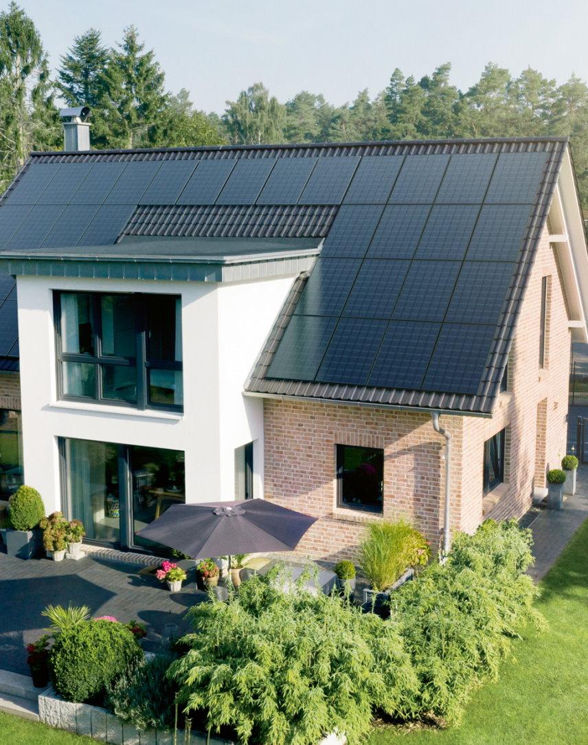 Haus mit Dach voller Solarmodule und einem hübschen Garten