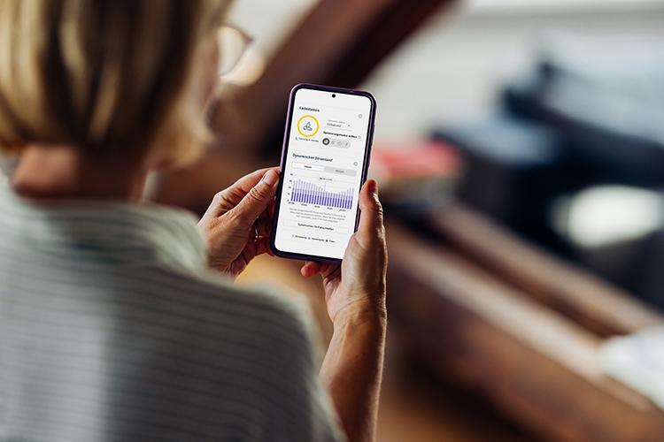 Frau mit Smartphone auf dessen Bildschirm der EWE Energiemanager abgebildet ist