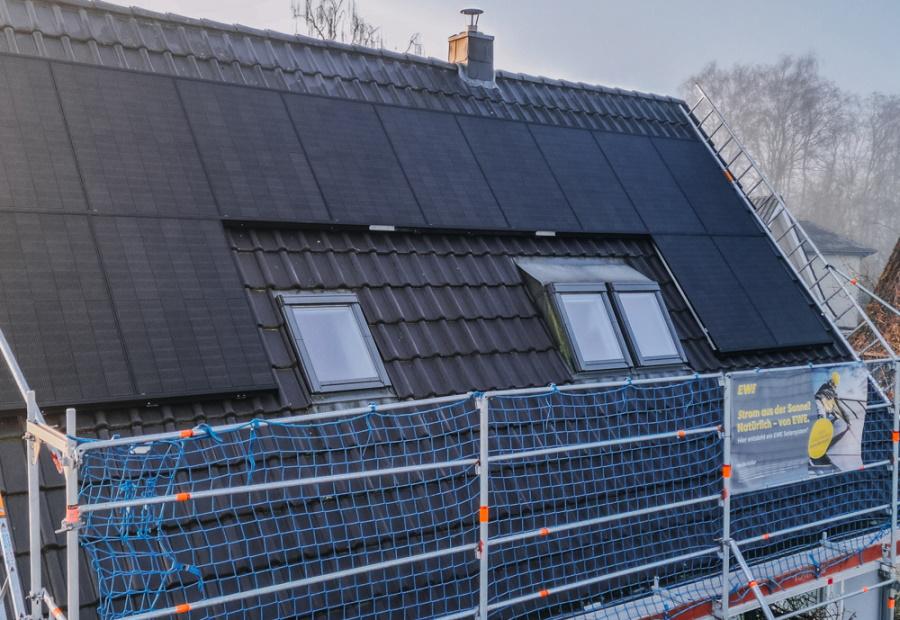 EWE-Mitarbeiter mit PV-Module auf dem Dach von EWE-Solarkundin Kerstin
