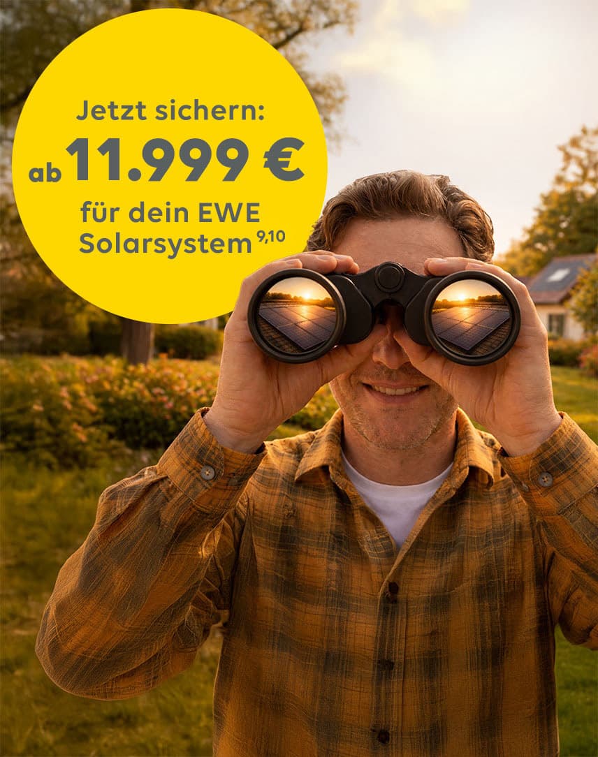 Mann steht in einer Sonnenblumenwiese vor einem Haus mit Solarsystem