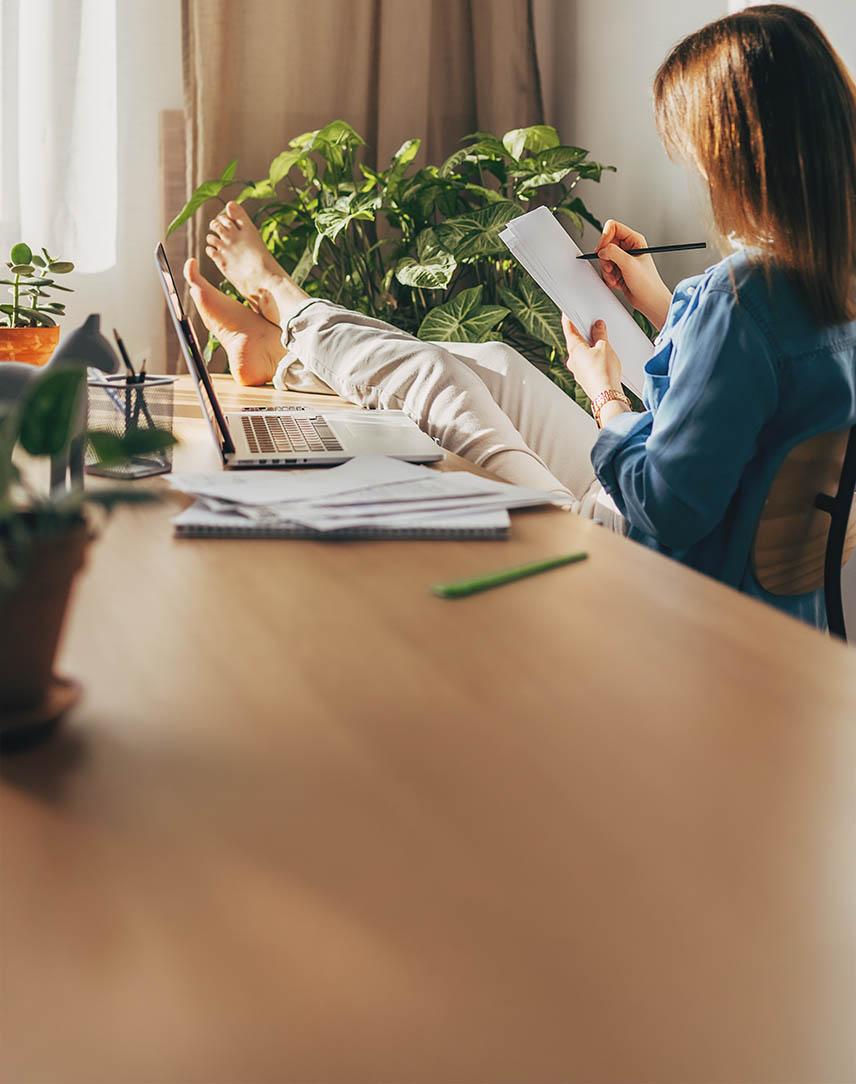 Frau legt die Füße auf dem Schreibtisch hoch und notiert sich etwas