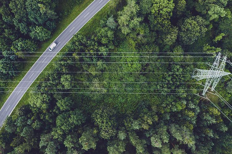 Straße, Wald und Stromleitung aus der Vogelperspektive