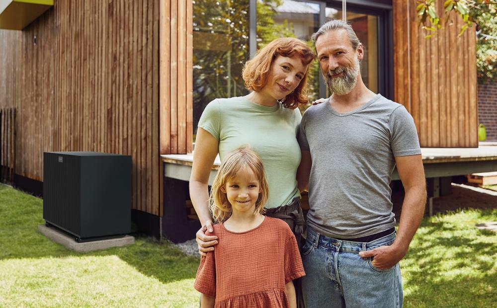 Familie steht vor Ihren Haus, neben dem sich eine Wärmepumpe befindet