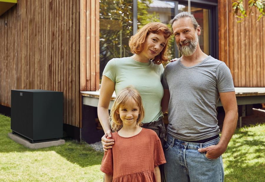 Familie steht vor Ihren Haus, neben dem sich eine Wärmepumpe befindet