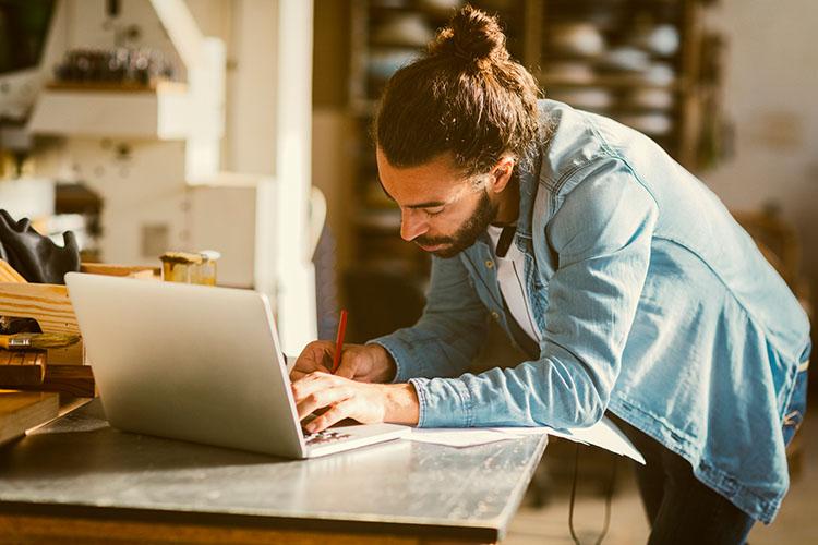 Mann arbeitet in Werkstatt am Laptop
