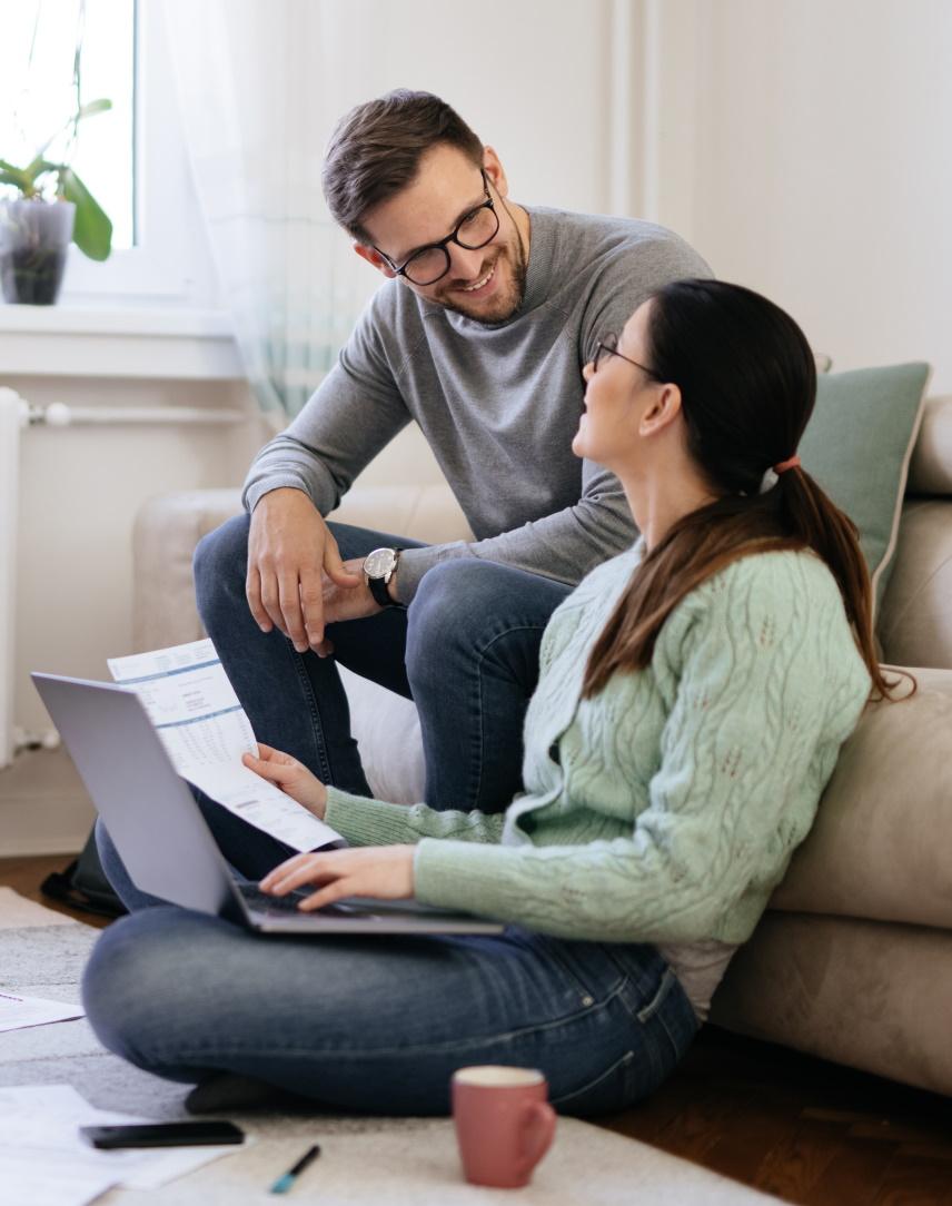Junges Pärchen mit Zetteln und Laptop auf einer Couch