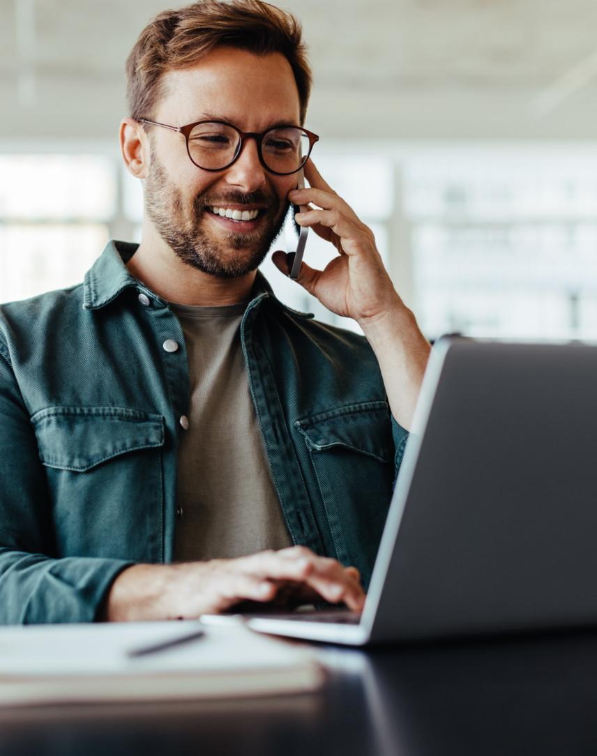 Junger Mann telefoniert und schaut dabei in seinen Laptop