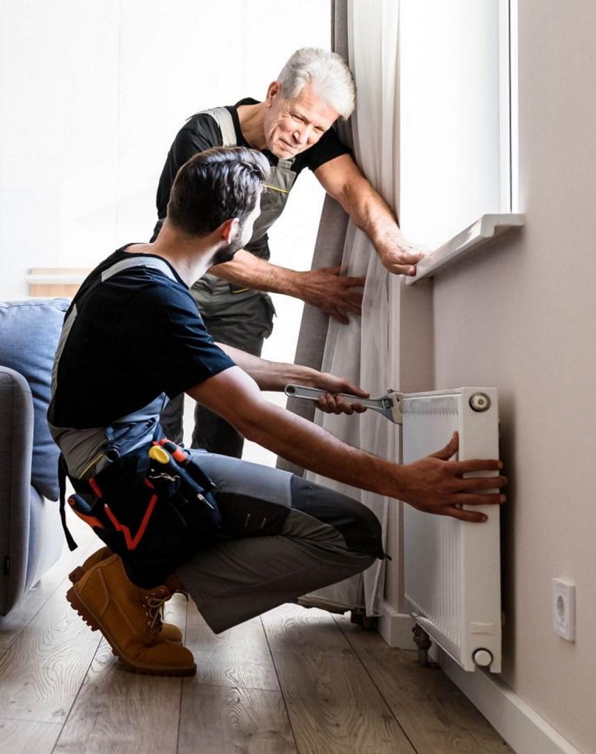 Zwei Handwerker installieren einen Heizkörper