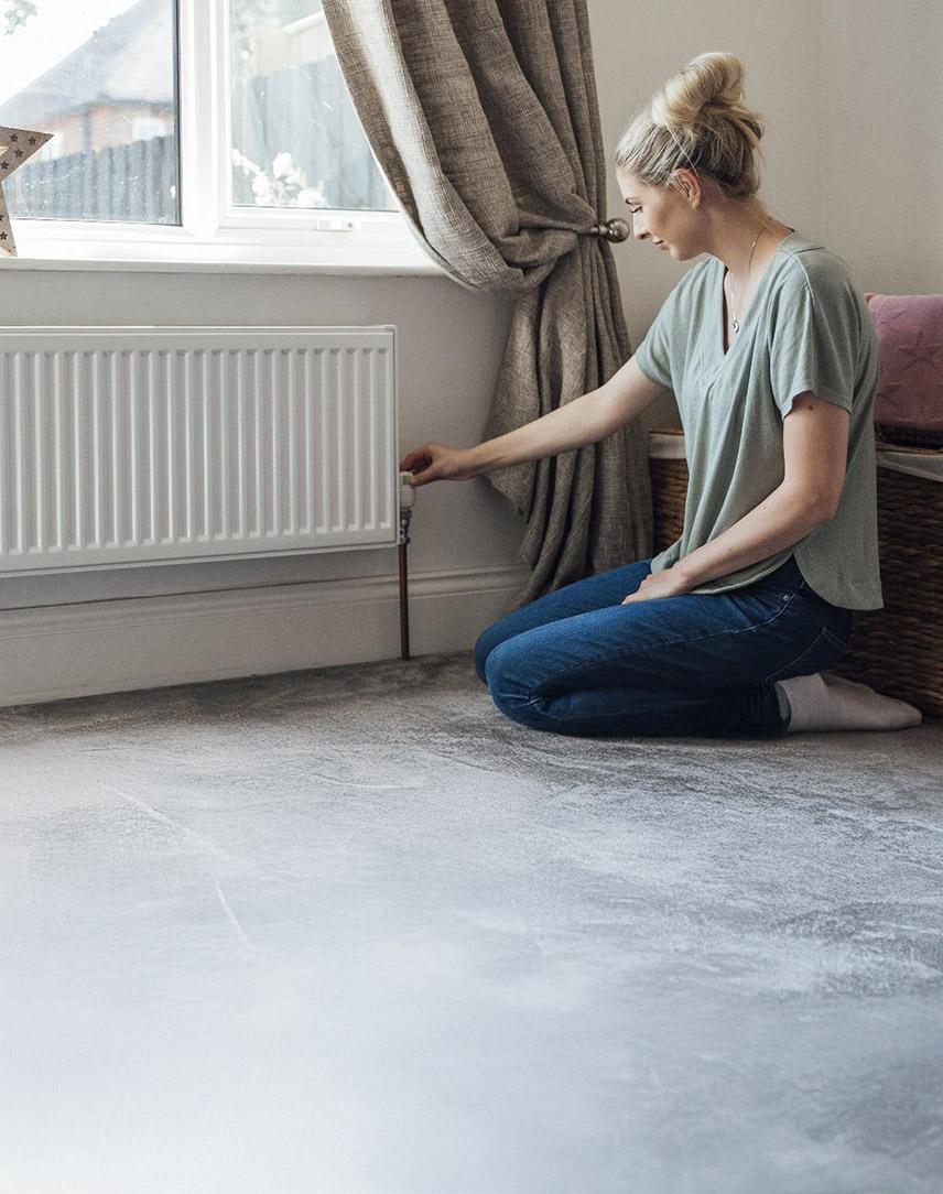 Frau dreht am Thermostat einer Heizung