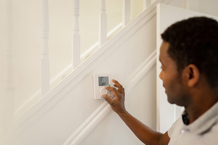 Mann stellt digitales Thermostat an einer Treppe ein