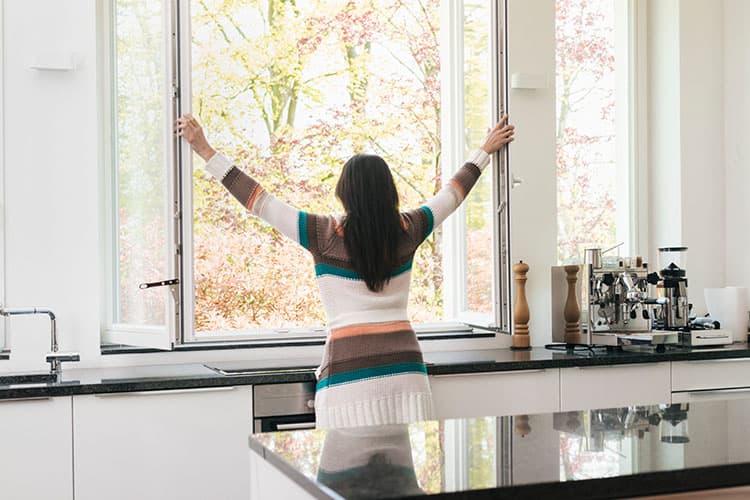 Frau öffnet die Fenster in der Küche
