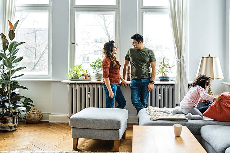 Pärchen lehnt an der Fensterbank an einer Heizung im Wohnzimmer