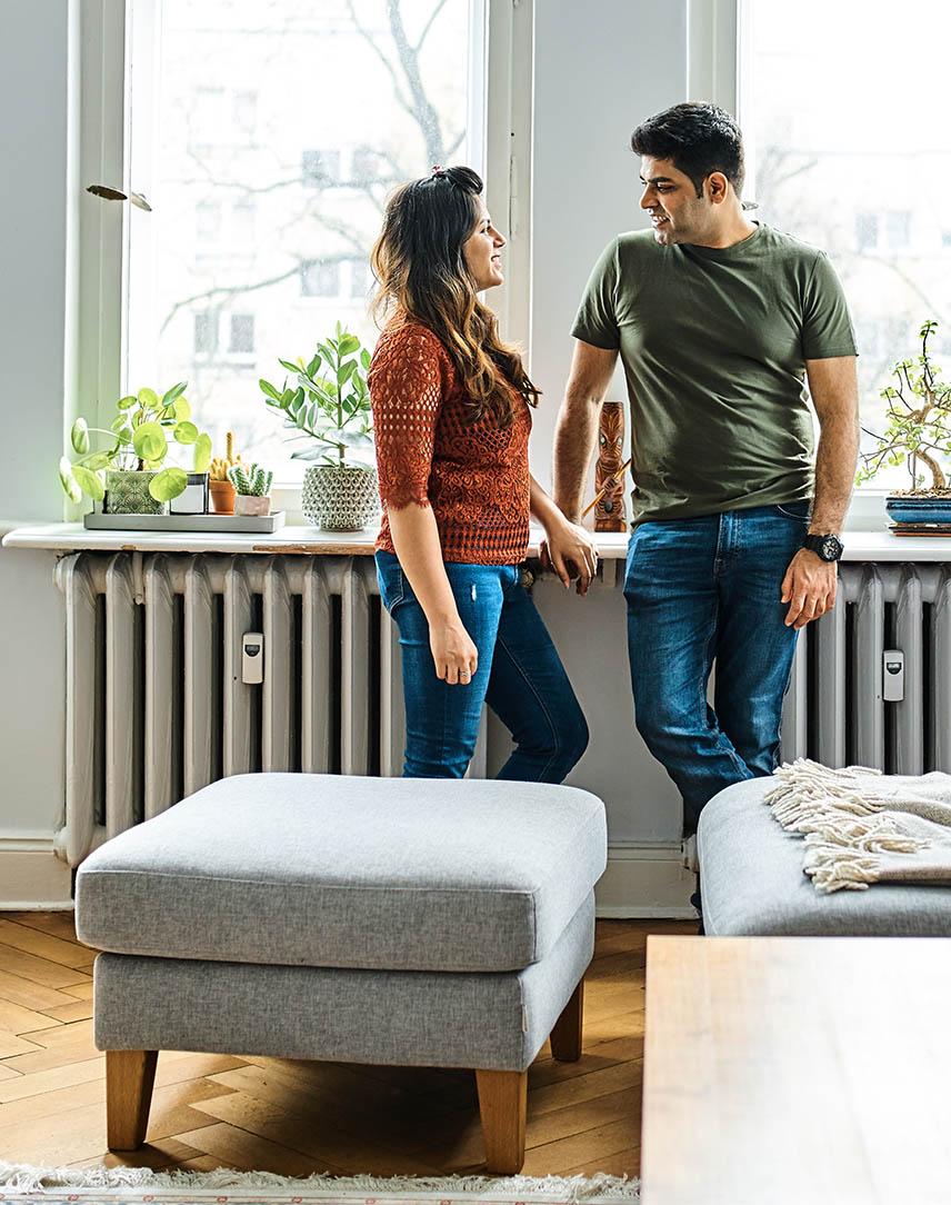 Pärchen lehnt an der Fensterbank an einer Heizung im Wohnzimmer