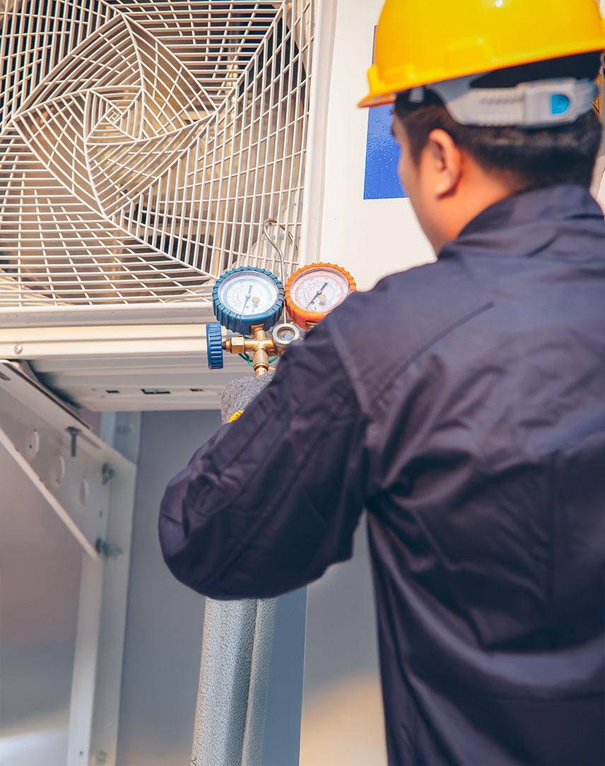 Mann mit Bauhelm prüft Wärmepumpe