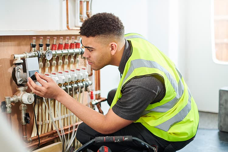 Mann mit Warnweste an einer Heizungsanlage