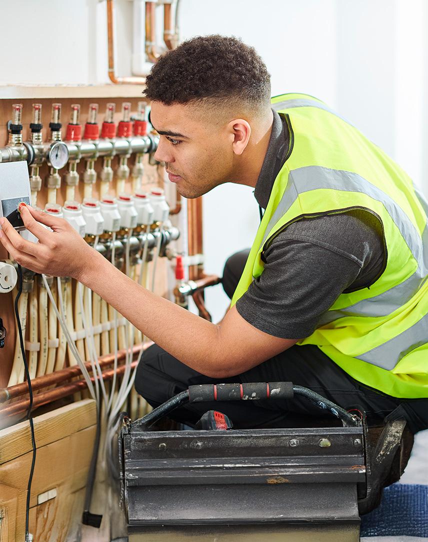 Mann mit Warnweste an einer Heizungsanlage