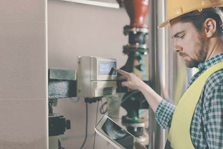 Mann mit Warnweste und Bauhelm prüft etwas an der Gasheizung