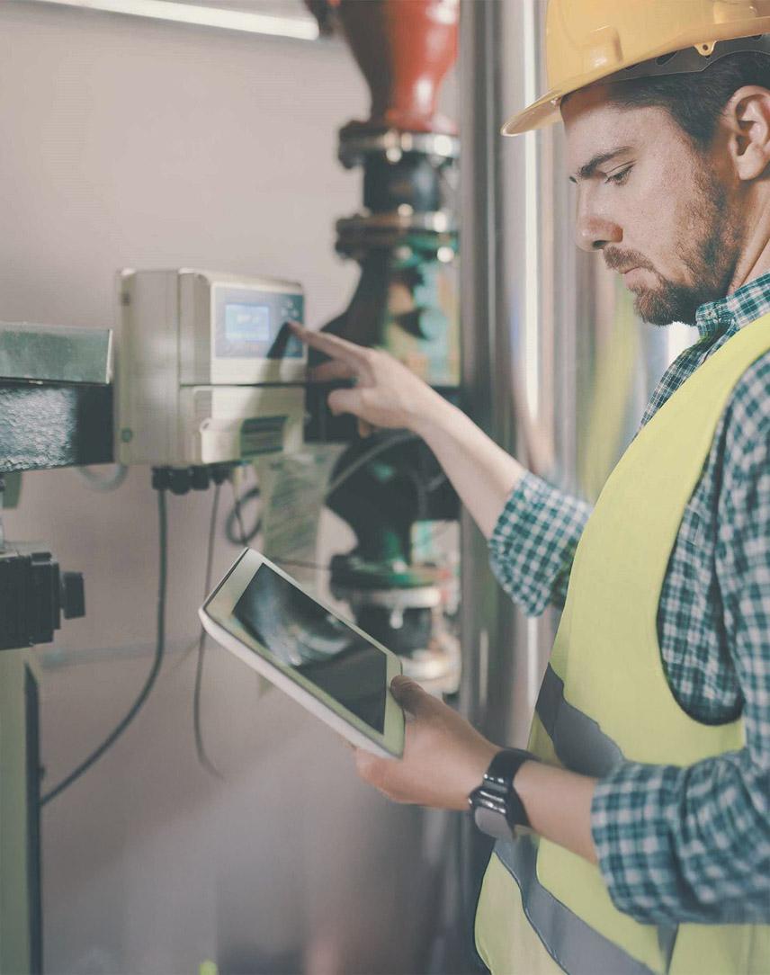 Mann mit Warnweste und Bauhelm prüft etwas an der Gasheizung