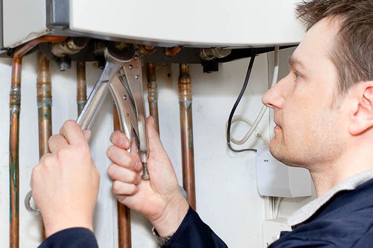 Mann arbeitet mit einer Zange an der Heizungsanlage