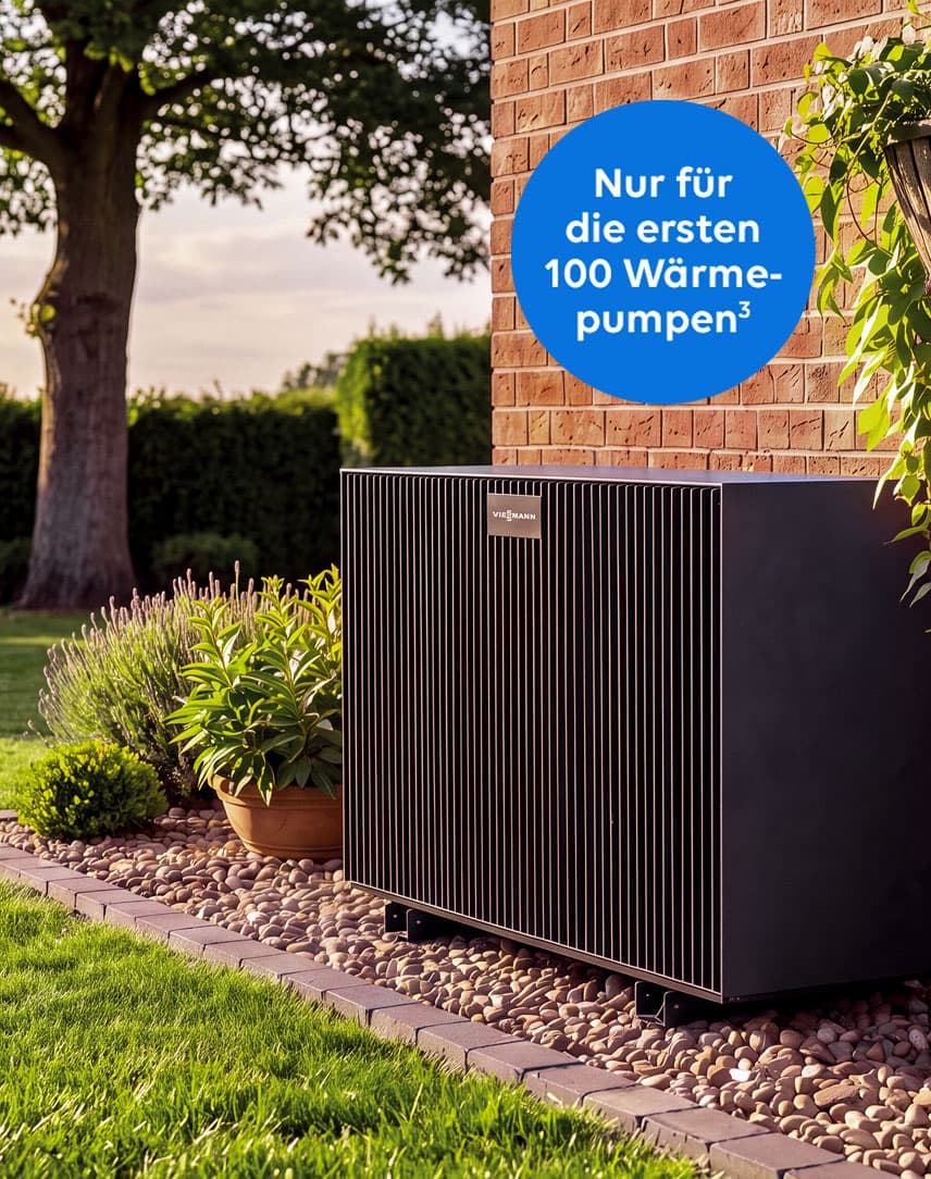 Wärmepumpe steht auf Kies vor roter Backsteinwand im Garten